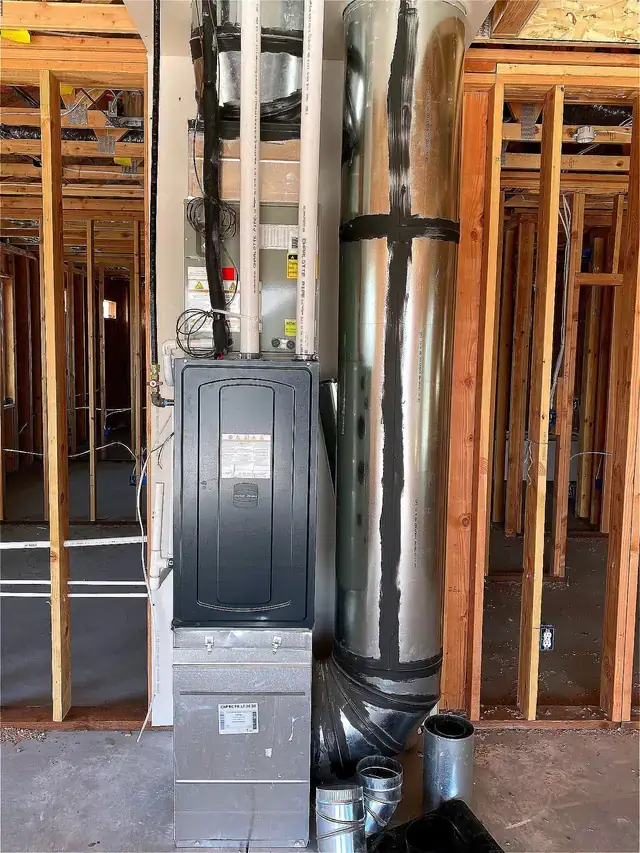 A new furnace and metal flue installed in a framed new-construction utility space