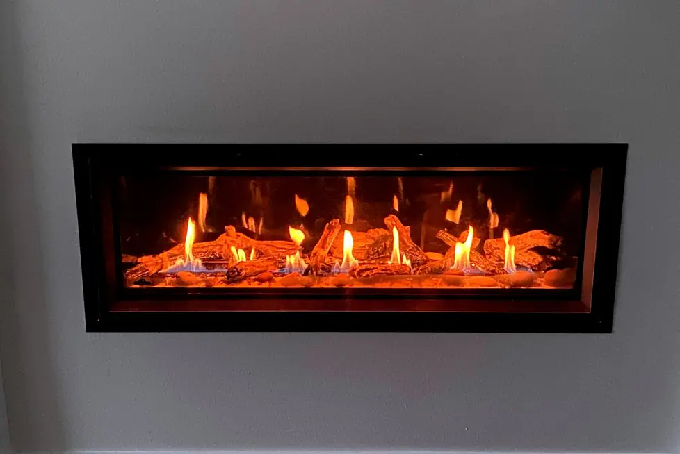 Lit linear gas fireplace set into a grey wall