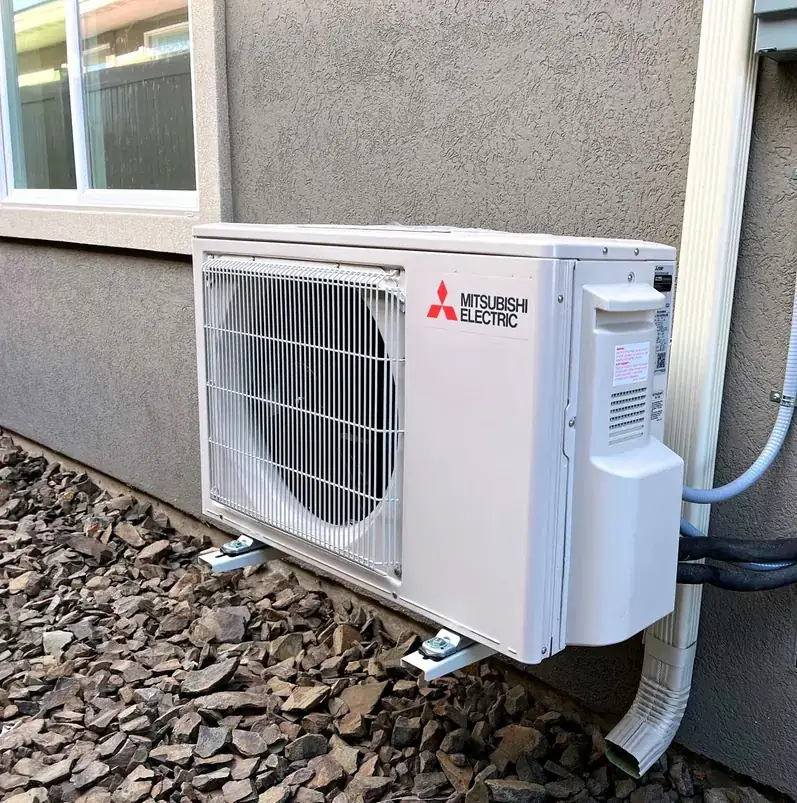 Mitsubishi outdoor unit on wall brackets against stucco